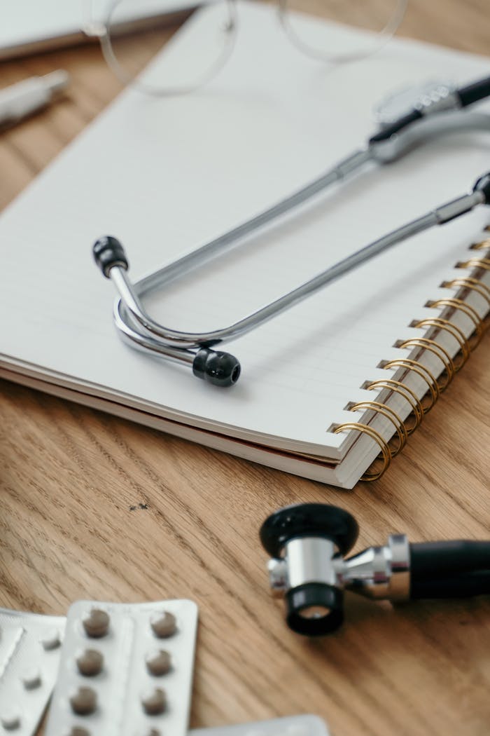Close-up of a stethoscope placed over a notebook with pills nearby, symbolizing healthcare themes.